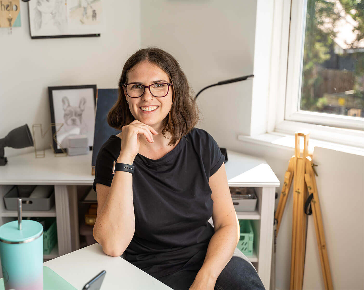 Kirsty sitting at a desk in a home office with a window in the background